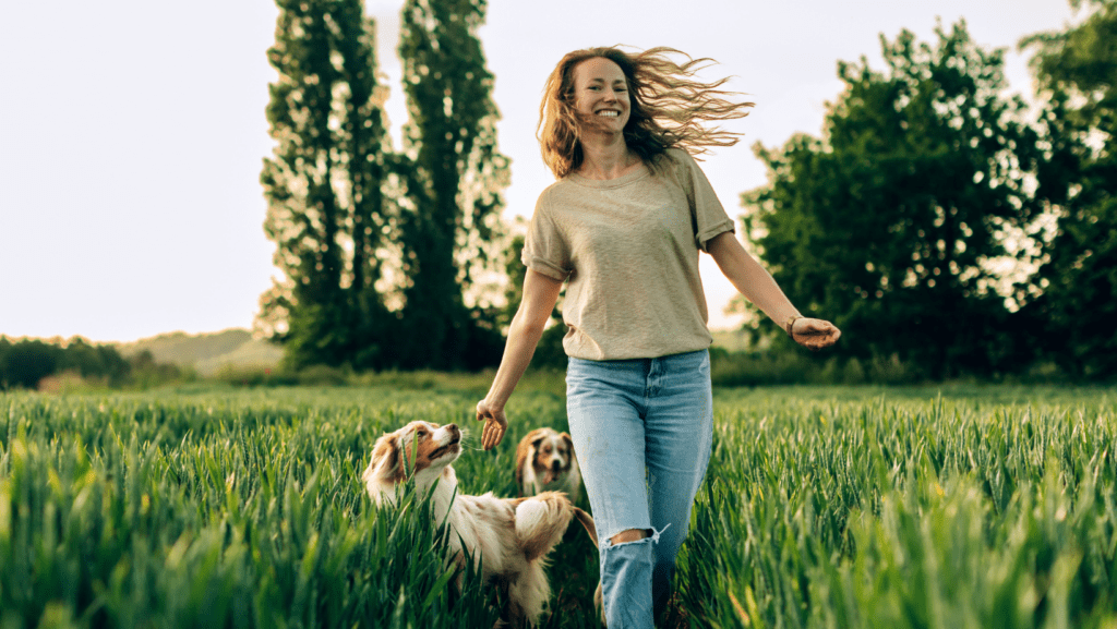 Happy owner running through field with pet dogs