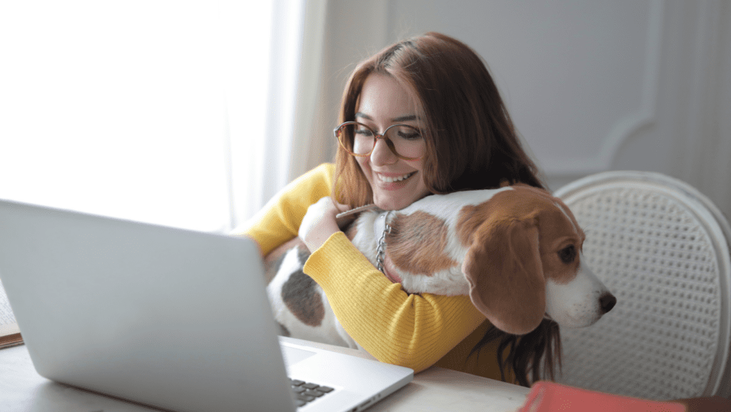 Lady happily working from home on laptop with dog