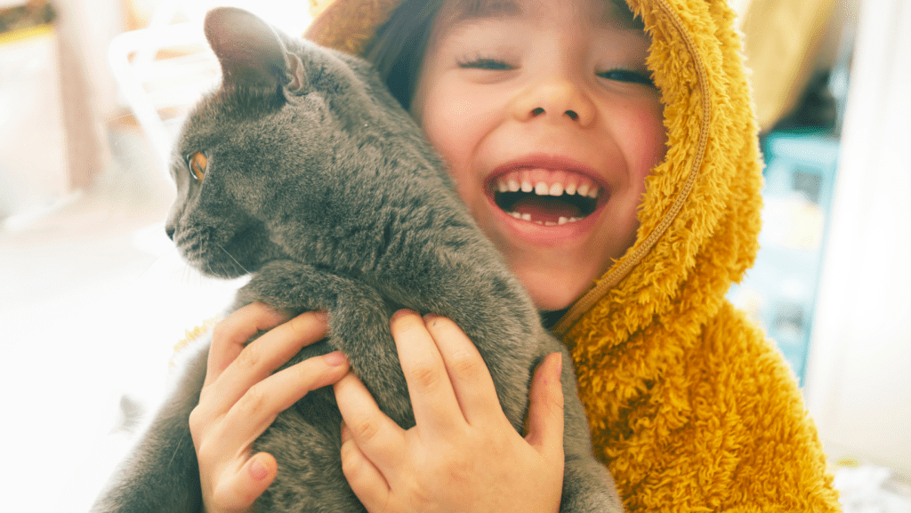 Young boy cuddling cat and laughing