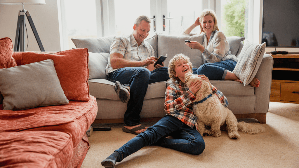 Little boy playing with his dog with parents happy nearby
