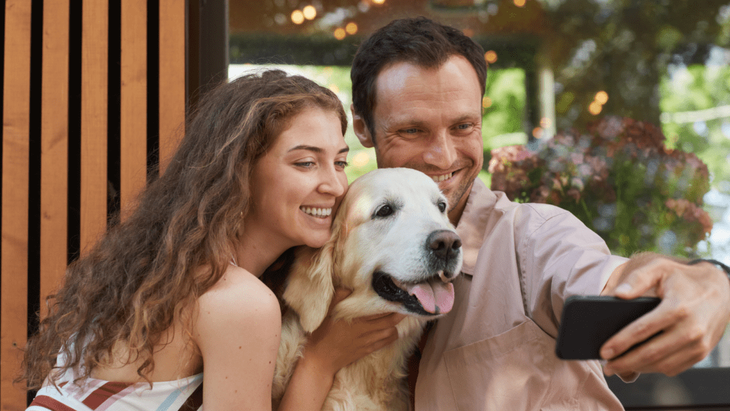 Image of a man and a woman taking a selfie with their adorable dog. The couple, beaming with affection, captures the deep bond between pets and owners. The image reflects the common assumption among pet lovers that everyone shares the same love for pets, showcasing the joy and companionship that pets bring into people's lives.