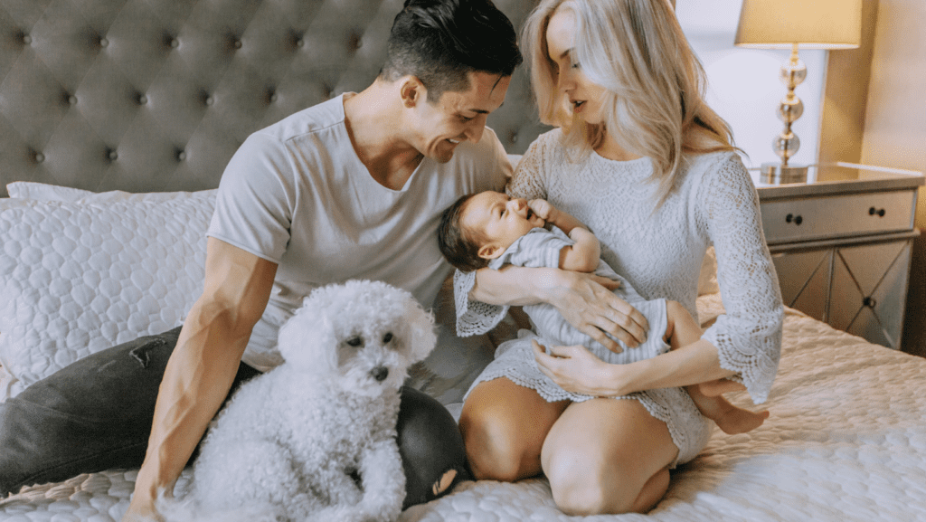 A loving couple cradling their newborn baby while their loyal dog stands by, illustrating the heartwarming embrace of family life.
