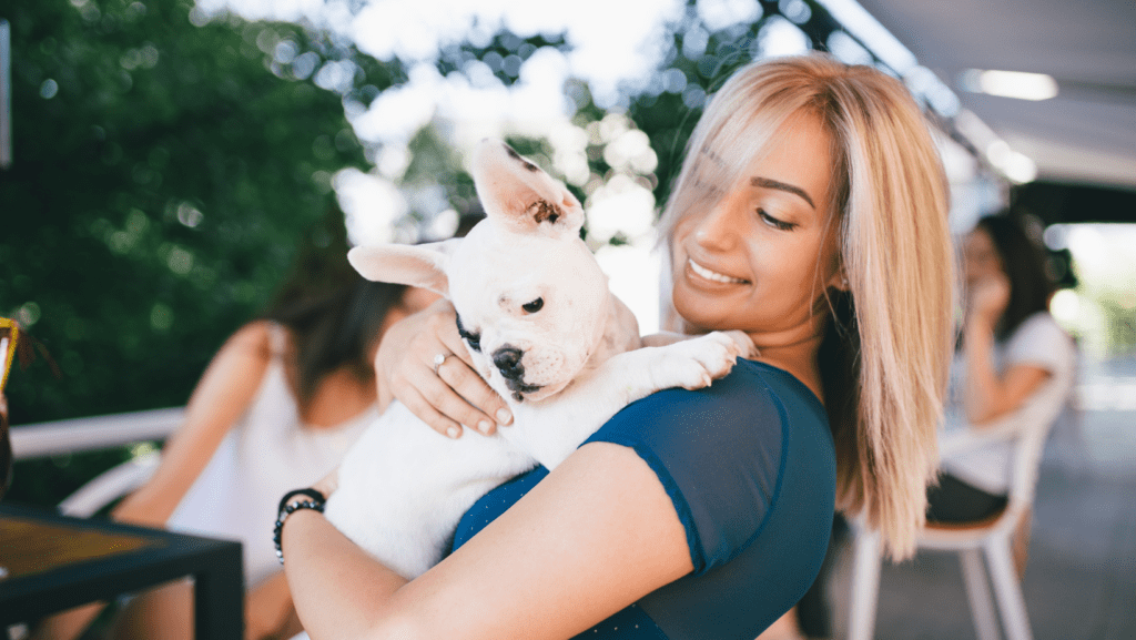 A young white dog with owner happily bonding.
