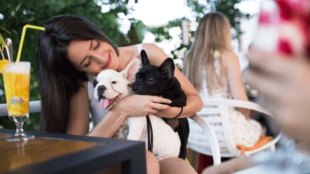 Lady with two dogs on her lap in a café looking happy